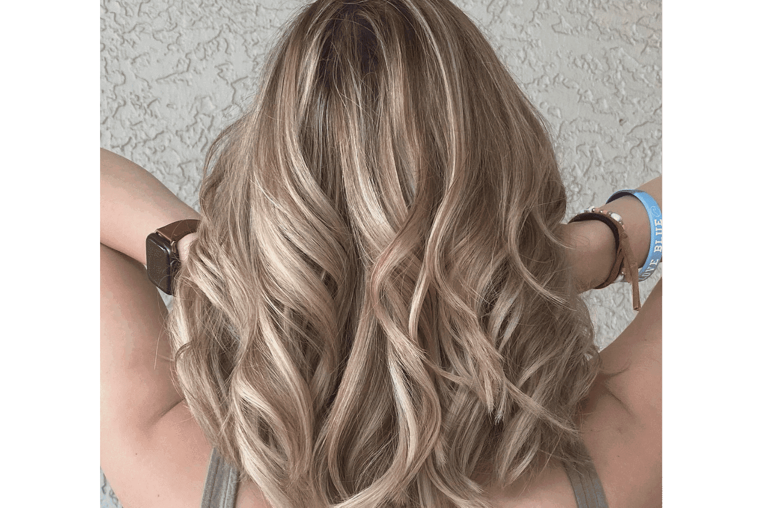 Wavy blonde hair from behind, styled with soft curls.