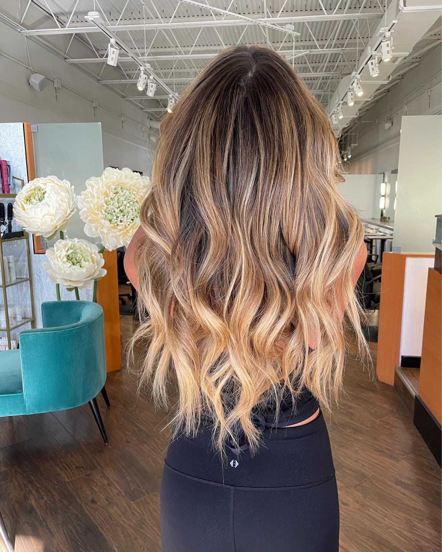 Woman with long, wavy, blonde hair in a chic salon setting.