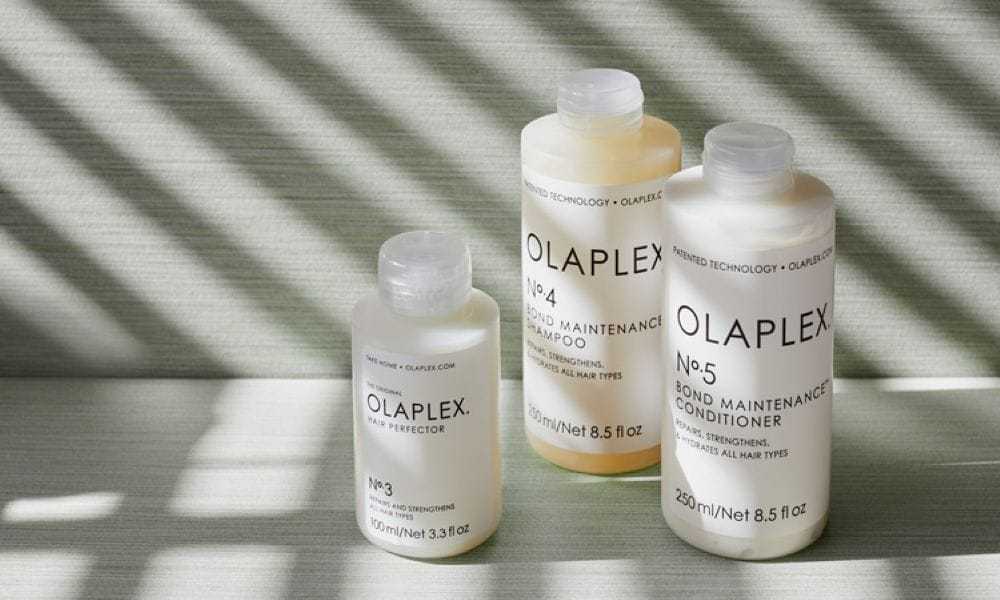 Olaplex hair care bottles arranged on a green surface with striped shadows.