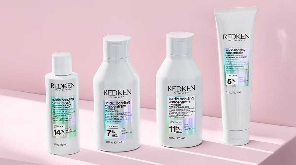 Redken Acidic Bonding Concentrate haircare products displayed on a pink background.